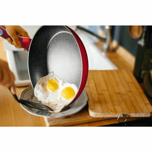 Red non-stick frying pan easily serving fried eggs