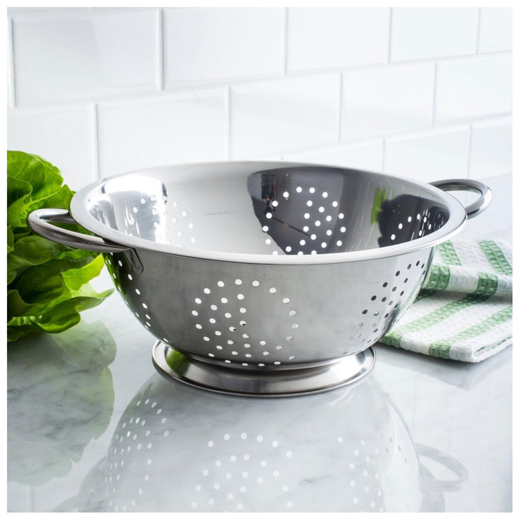 Stainless steel colander with lettuce on a marble countertop.
