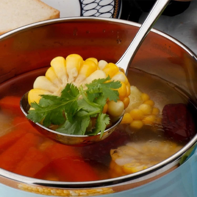 Stainless steel ladle serving corn and soup.