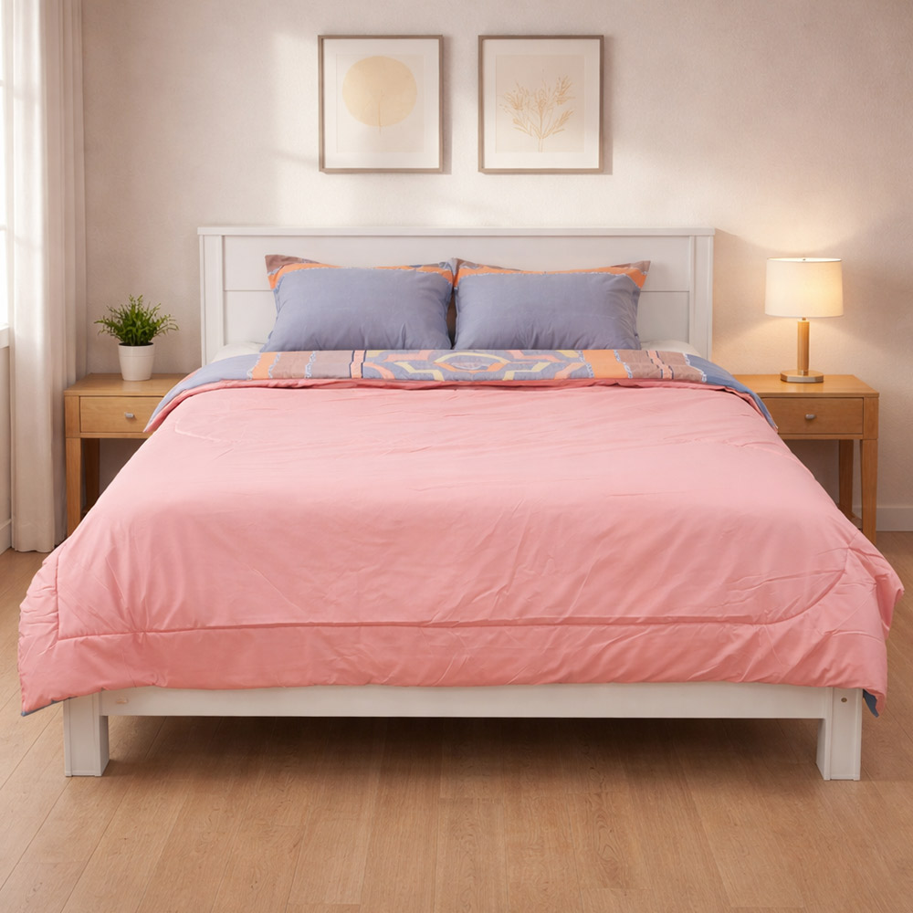 Christy’s pink reversible comforter set on white bed