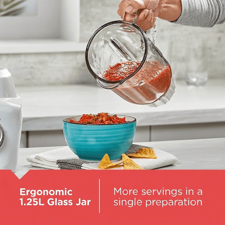 Glass blender jar pouring salsa into bowl.