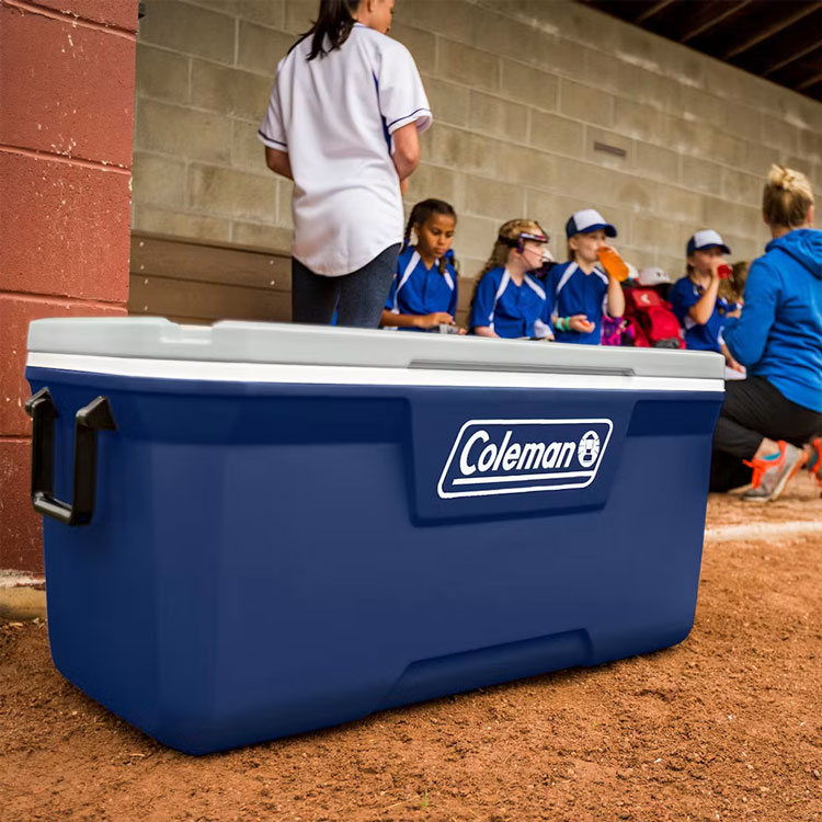 Blue large Coleman cooler sitting on dirt field
